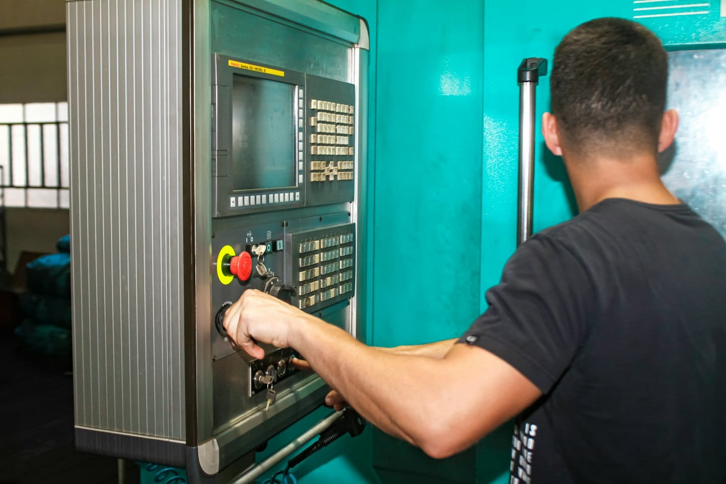 Fabrika makinesi kontrol paneliyle uğraşan eller.